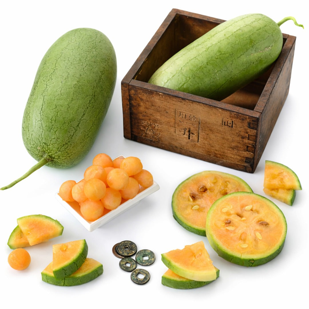 Kaho watermelon in a wood box with surrounding melons, melon slices, and melon balls in a white dish.