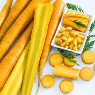 Cut and whole Jaune Obtuse du Doubs carrots on a white background.