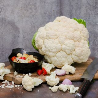 Amazing Cauliflower head next to roasted cauliflower and peppers on wooden board.