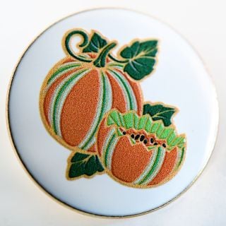 A close-up view of a Baker Creek Kajari Melon Limited Edition Pin on a light background. A close-up view of a Baker Creek Kajari Melon Limited Edition Pin on a light background.