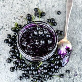 Chichiquelite Huckleberry jam with berries and spoon on a stone background.