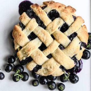 Garden Huckleberry pie with a few berries on the side on top of a white background