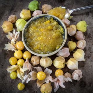 Aunt Molly's Ground Cherry fruit with prepared jam in a bowl on a wooden background.
