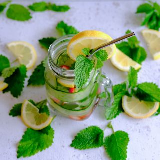Green Lemon Balm leaves in cucumber water on light countertop.