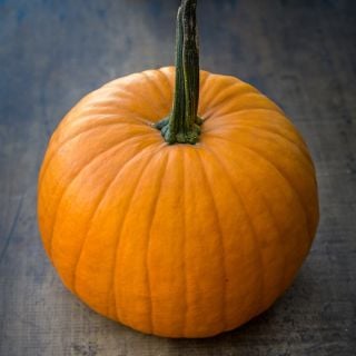 A single Connecticut Field Pumpkin Winter Squash on a wood background.