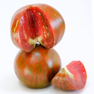 Cut and whole Large Barred Boar Tomatoes on a high key background.