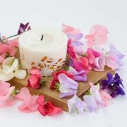 Old Spice Mix Sweet Pea flowers and candle on a wooden cutting board.