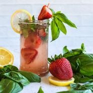 Old North Sea Strawberry and basil lemonade in a frosted mason jar with a whole strawberry, fresh basil and lemons.