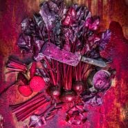 Overhead view of gory Bull's Blood Beets scene with a rusty butcher's knife covered in beet juice.