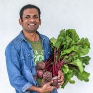 A MESA intern from Sri Lanka smiles and holds a bunch of freshly harvested Crosby's Egyptian Beets.