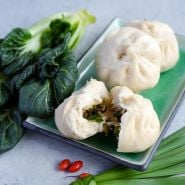 A head of Chijimisai with three Chijimisai soft buns on a green plate.