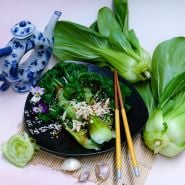 Steamed Suzhou Baby Bok Choy leaves on a plate with fresh heads and vintage Chinese teapot.