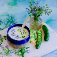 Blue borage flower and cucumber soup on a light blue background. 