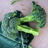 A couple of Calabrese Green Sprouting Broccoli heads on a terra cotta pizza round.