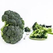 Cooked and raw Rasmus Broccoli with a fork on a white backgrouund.