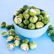 A blue bowl of Long Island Improved Brussels Sprouts on a light blue background.