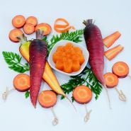 Whole and sliced Purple Dragon Carrots with carrot jello on a white background.