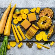 Yellow colored Jaune Obtuse du Doubs Carrots with cup-ups and carrot jelly on a stone board. 