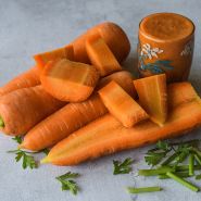 Cut, whole and juiced Koral Carrots on astone background.