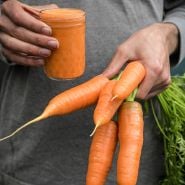 A man holding Koral Carrots with cup of carrot juice.