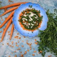 Little Finger Carrots  on plate with carrot top greens on side.