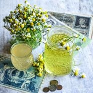 German Chamomile tea and kombucha with flowers and vintage German money on a white wooden background.