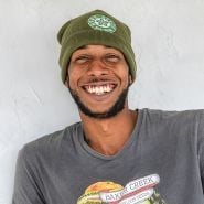 A Baker Creek manager smiles while wearing a Baker Creek Logo Beanie.