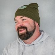 The Baker Creek general manager smiling while wearing a Baker Creek Logo Beanie.