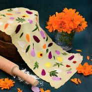 Cosmic Orange Cosmos with some pasta dough with flower petals on it with a rolling pin and flour.
