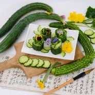 Suyo Long Cucumber sliced and presented on white plate with blooms.