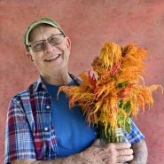 A speaker poses with some celosia at the Baker Creek Fall Harvest Festival.