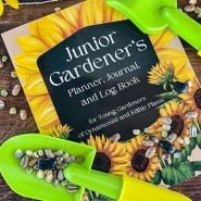 A Junior Gardener's planner booklet with child's gardening tools and scattered seeds.
