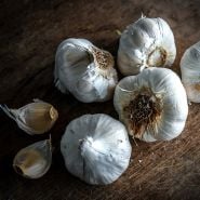 Early Italian Purple Garlic bulbs and cloves on a wooden cutting board.