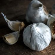 A close-up of Early Italian Purple Garlic bulbs and cloves on wood.