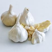 Whole and cut Inchelium Red Garlic bulbs and cloves on a white background.