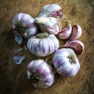 An arrangement of Vietnamese Red Garlic bulbs with cloves on wooden background.