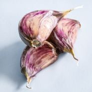 A macro view of a trio of Vietnamese Red Garlic cloves on light background.