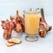 Thai Galangal roots with a refreshing glass of Thai Galangal/green apple artison soda on a light background.