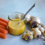 Thai Ginger and carrot salad dressing with ginger roots on a light blue background.
