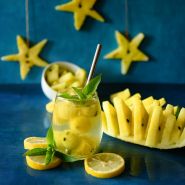 A Lemon Drop Watermelon drink with melon balls and slices on a dark background.
