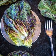 Flashy Butter Gem Lettuce leaves on a pewter plate with with fork on a dark background.