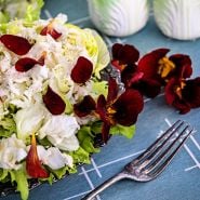 Edible Black Velvet Nasturtium petals on top of a bed of Ice Queen lettuce with a fork.