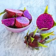 Cut and whole Edgar's Baby Dragon Fruit in a pink bowl and arranged on marble background.