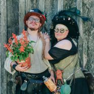 A couple holding plants and dressed up in cool outfits at the Baker Creek Spring Planting Festival.