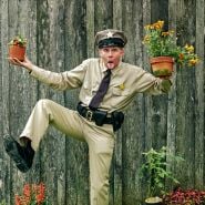 Terry Sanders poses in his Barney Fife outfit whie balancing plants at the Baker Creek Spring Planting Festival.