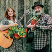 A couple of musicians pose with plants and guitars at the Baker Creek Spring Planting Festival.