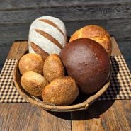 Assorted  loaves of bread made from Ms. Debbie’s Rye Starter in a basket on a wood table.