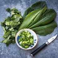 Spinach Mustard "Old Tokyo" Komatsuna leaves and chopped stems in a bowl on a grey background.