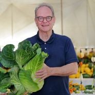 A speaker smiles while holding a large cabbage at the Baker Creek Fall Harvest Festival.