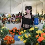 A smiling young woman poses with flowers at the Baker Creek Fall Harvest Festival.
